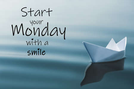 Motivational quote Start your Monday with a Smile and white paper boat floating on riverの写真素材