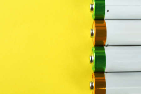 New AA batteries on yellow background, flat lay. Space for text