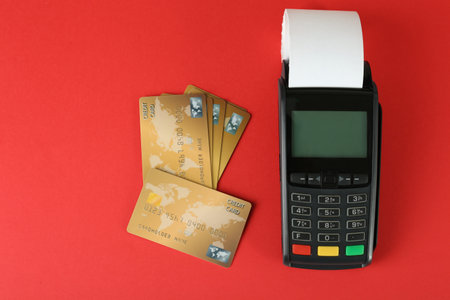 New modern payment terminal and credit cards on red background, flat layの写真素材