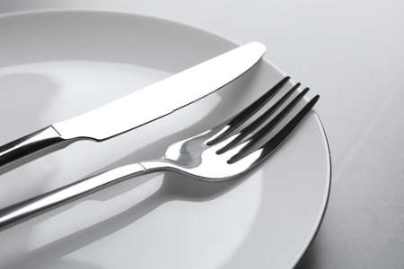 Plate with fork and knife on light gray table, closeupの写真素材