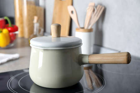 Saucepan with lid on cooktop in kitchen, closeup view. Cooking utensilの写真素材