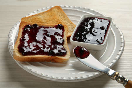 Delicious toasts with jam served on white wooden table, closeup