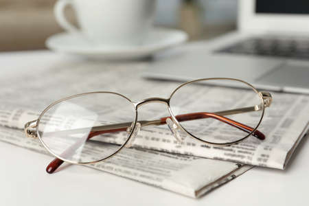 Newspapers and glasses on white table, closeupの写真素材