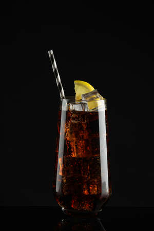 Glass of refreshing soda water with ice cubes and lemon slice on black backgroundの写真素材