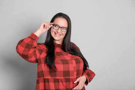 Beautiful overweight woman in eyeglasses on light gray background. Space for text