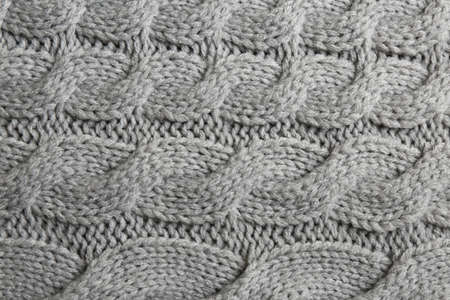 Gray knitted fabric with beautiful pattern as background, top view