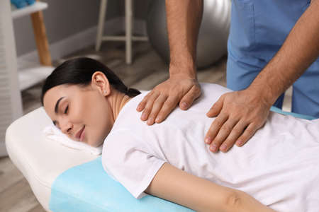 Orthopedist massaging young woman's back in clinic, closeup. scoliosis treatment