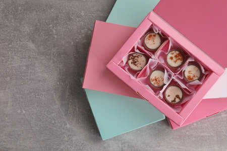 Delicious chocolate candies and box on light gray table, top view with space for text. production...