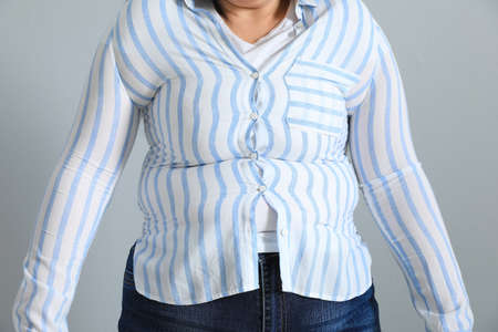 Overweight woman in tight shirt on light gray background, closeupの写真素材