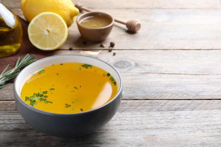 Bowl with lemon sauce and ingredients on wooden table, space for text. Delicious salad dressingの写真素材