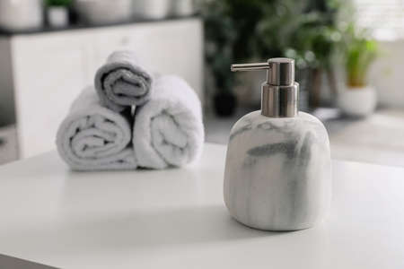 Dispenser with liquid soap near towels on white table in bathroom, space for textの写真素材