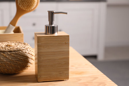 Dispenser with liquid soap near wicker box on wooden table in bathroom, space for textの写真素材