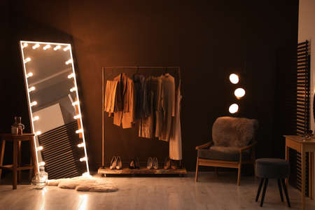 Stylish mirror with light bulbs and comfortable armchair in dressing room. interior designの写真素材