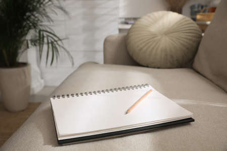 Notebook and pencil on light gray sofa in living roomの写真素材