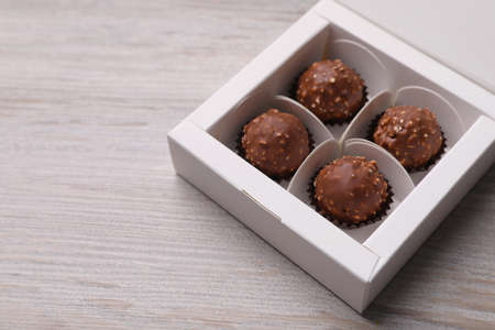 Delicious chocolate candies in box on white wooden table, space for textの写真素材