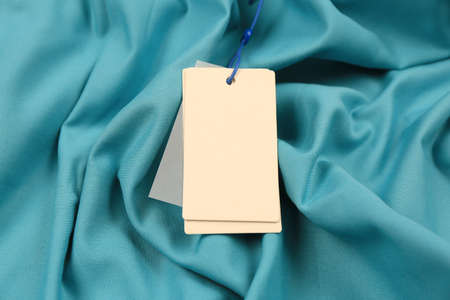 Blank white tags on light blue fabric. Space for textの写真素材