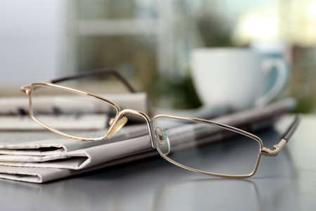 Stack of newspapers and glasses on gray table indoors, closeupの写真素材