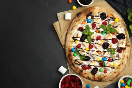 Tasty sweet pizza and ingredients on black table, flat lay. Space for textの写真素材