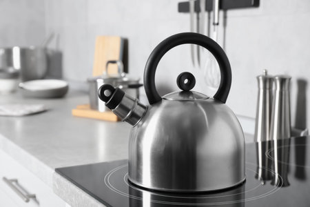 Stainless steel kettle on electric stove in kitchenの写真素材