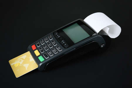 New modern payment terminal with credit card on black background
