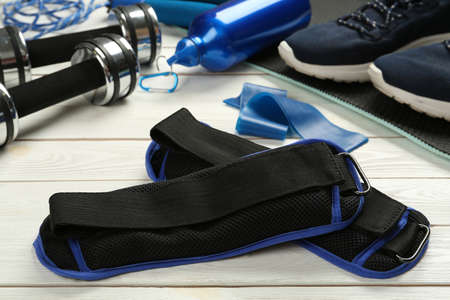 Blue weighting agents and sports equipment on white wooden table