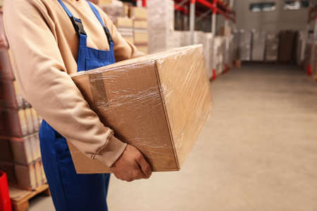 Worker with cardboard box in warehouse, closeup. Wholesalingの写真素材