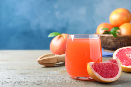 Tasty freshly made grapefruit juice and fruit on wooden table. Space for textの写真素材