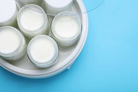 Modern yogurt maker with full jars on light blue background, top view. Space for textの写真素材