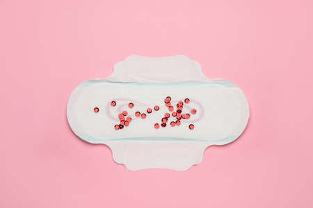 Menstrual pad with red sequins on pink background, top viewの写真素材