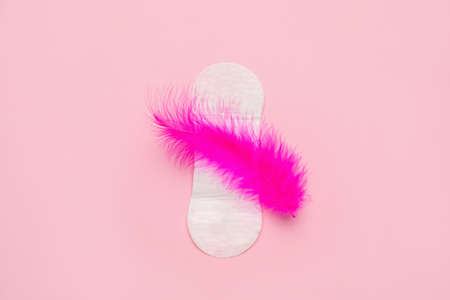 Sanitary pad with feather on pink background, top view. menstrual cycleの写真素材