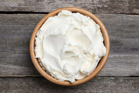 Bowl of tasty cream cheese on wooden table, top viewの写真素材