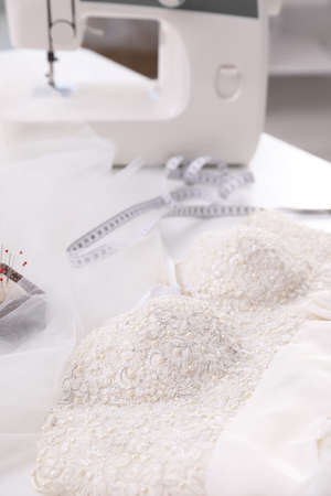 Beautiful wedding dress with embroidered bustline on table in dressmaking workshopの写真素材