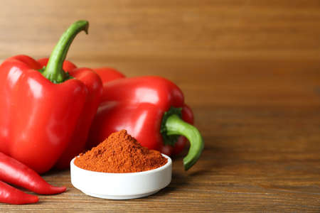 Paprika powder and fresh peppers on wooden table. Space for textの写真素材