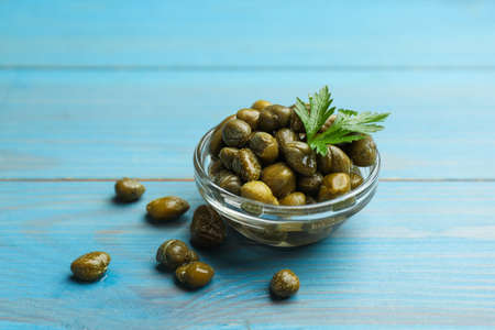 Tasty capers and parsley on light blue wooden tableの写真素材