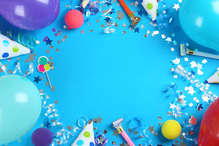 Frame of colorful serpentine streamers and other party accessories on light blue background, flat lay. Space for textの写真素材