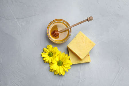 Natural beeswax, honey and flowers on light gray stone table, flat layの写真素材