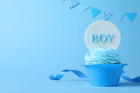 Beautifully decorated baby shower cupcake with cream and Boy topper on light blue background. Space for textの写真素材