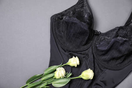 Elegant black plus size women's underwear and beautiful eustoma flowers on gray background, top view. Space for textの写真素材