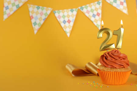 Coming of age party - 21th birthday. Delicious cupcake with number shaped candles on orange background, space for textの写真素材