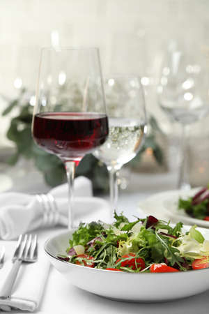 Delicious salad and wine served on table in restaurantの写真素材