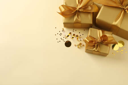 Beautifully wrapped gift boxes and confetti on beige background, flat lay. Space for text