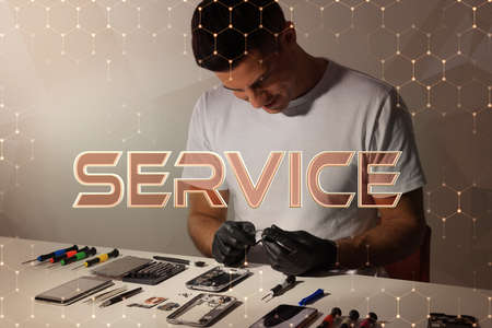 Technician repairing broken smartphone at table indoorsの写真素材