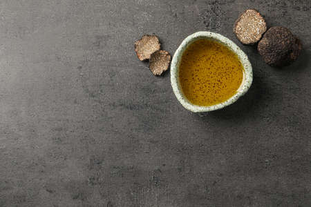 Fresh truffles and oil in bowl on gray table, flat lay. Space for textの写真素材