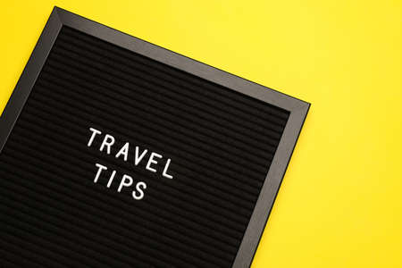 Black letter board with phrase Travel Tips on yellow background, top viewの写真素材