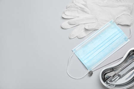 Set of different dentist's tools, face masks and gloves on light gray background, flat lay. Space for textの写真素材