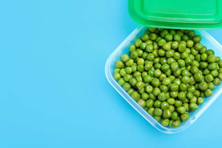 Fresh peas in glass container on light blue background, top view. Space for textの写真素材