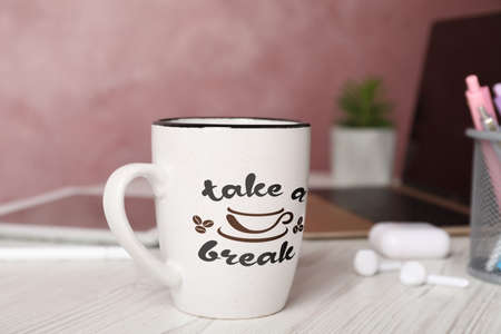 Cup of coffee with inscription Take a Break on white wooden table in officeの写真素材