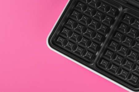 Modern electric waffle maker on pink background, top view. Space for textの写真素材