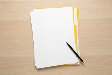 Yellow file with blank sheets of paper and pen on wooden table, top view. space for designの写真素材