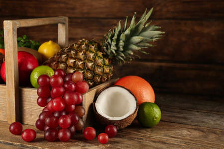Crate and different ripe fruits on wooden table. Space for textの写真素材